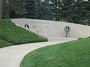 An arching stone wall is set into a small grass-covered hillside. The wall is engraved thus: