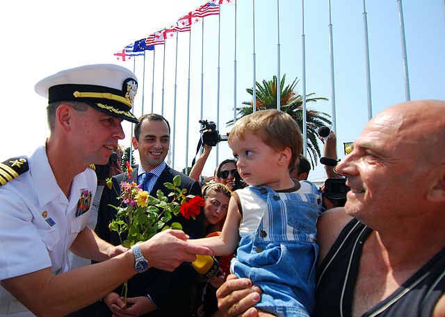 File:US Navy 080824-N-4044H-059 Capt. John Moore, commodore, Combined Task Force (CTF) 367, greets local residents and receives flowers shortly after the arrival of the guided-missile destroyer USS McFaul (DDG 74) to the port of Bat.jpg